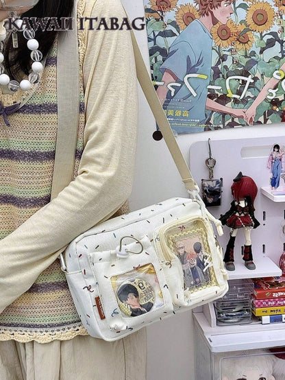 Cream confetti ita crossbody worn as shoulder bag with anime pins displayed in dual windows, styled with crochet top