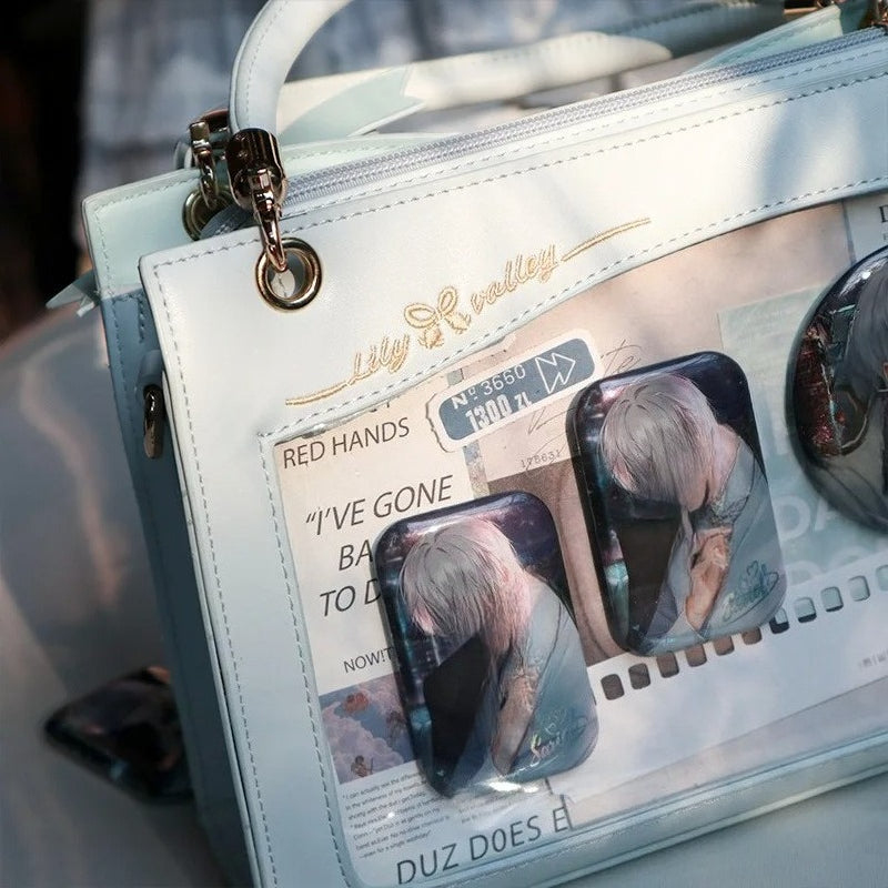 Close-up of light blue ita bag display window showing anime newspaper print