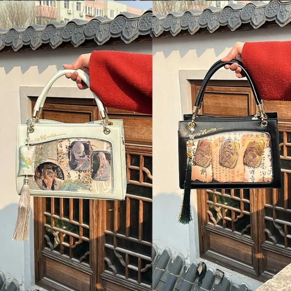 Cream and black ita handbags held up showing front display windows with tassels