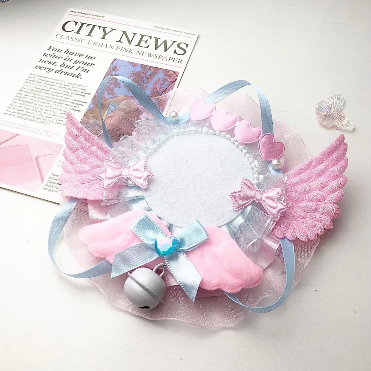 Pink blue angel wing badge holder frame on newspaper background