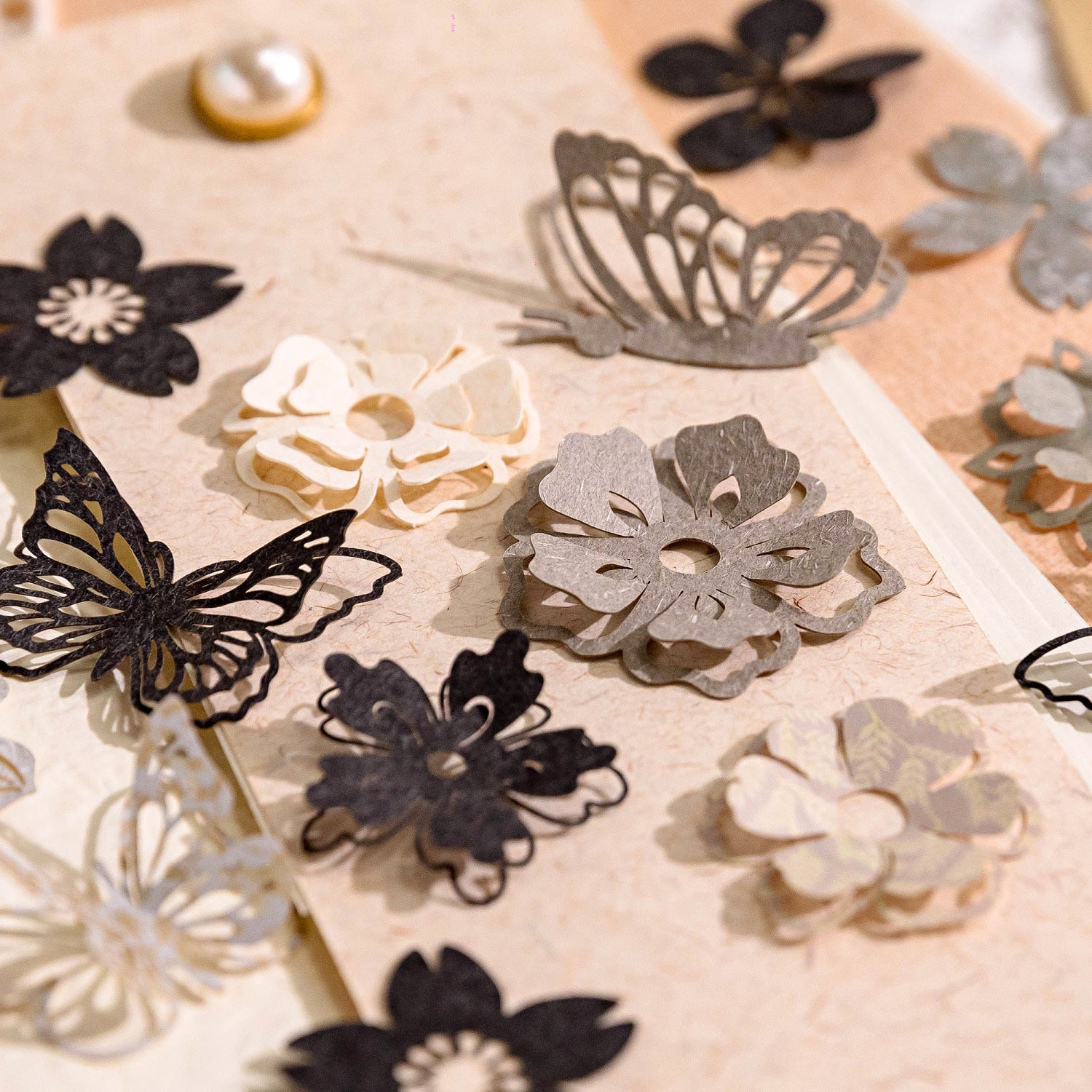 Black and grey paper flower and butterfly die cuts on kraft paper