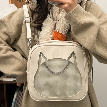 Cream white cat ear ita bag with cat-head shaped clear display window and silver decorative chain, worn as a crossbody.