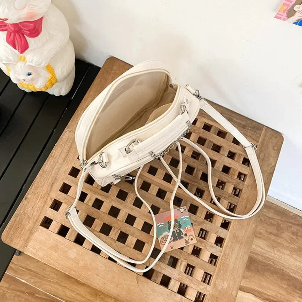 Rear view of the cream cat ear bag showing 3-way convertible strap D-rings and reinforced top handle