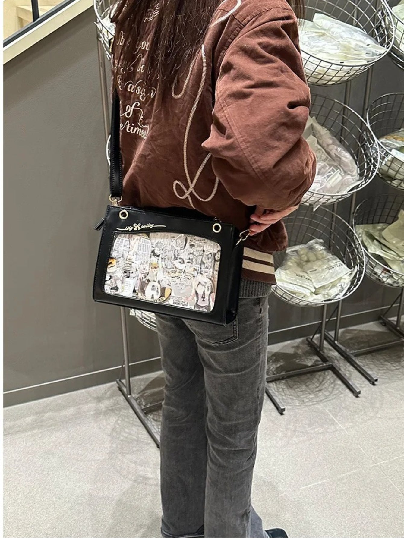 Person wearing brown hoodie carrying black ita bag crossbody with anime art